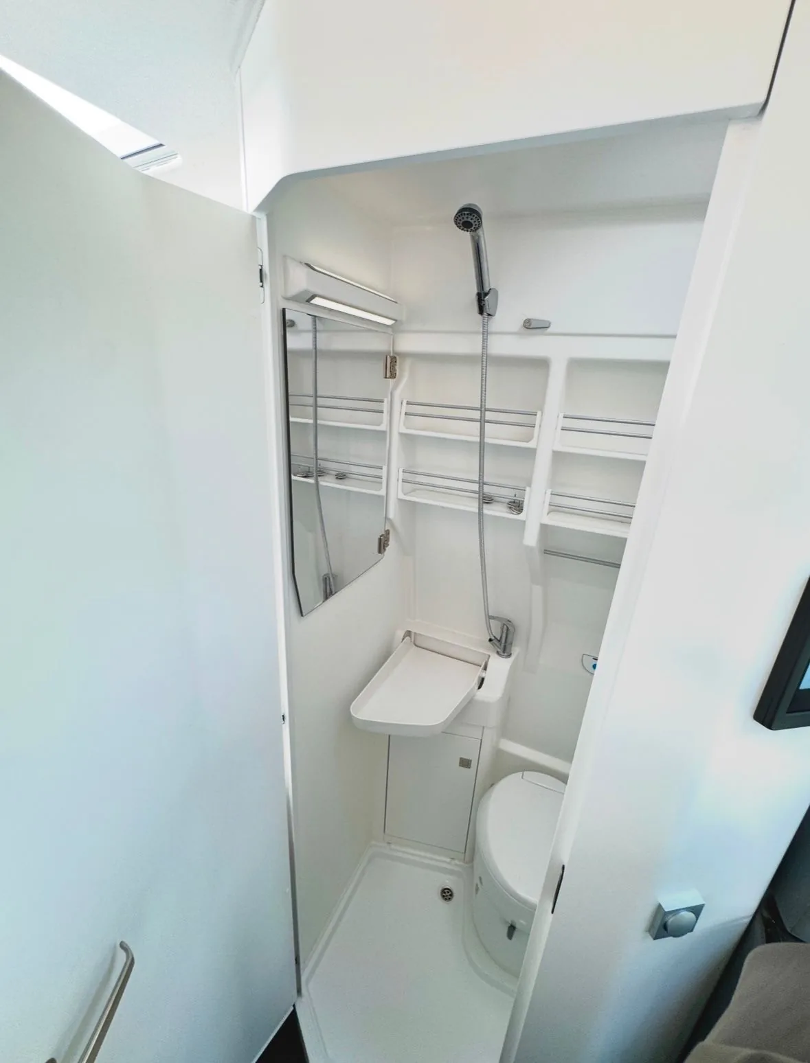 Kompakte Duschkabine mit Brause, Spiegel und Ablageregalen im VW Grand California