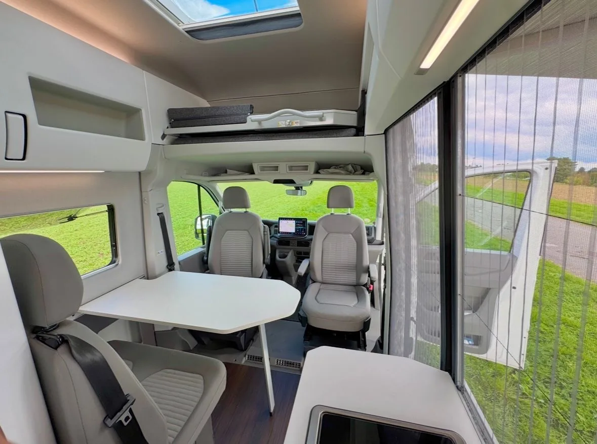 VW Grand California Innenraum mit geöffneter Schiebetür und Fliegenvorhang – Sitzbereich und Hängebett